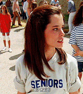 Parker Posey is wearing a shirt that says "Seniors" and screams "AIR RAID!" Gif from Dazed and Confused (1993)